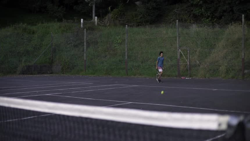 Boy Playing Tennis on Rural Outdoor Court Under Sunny Clear Sky, Sports Footage.