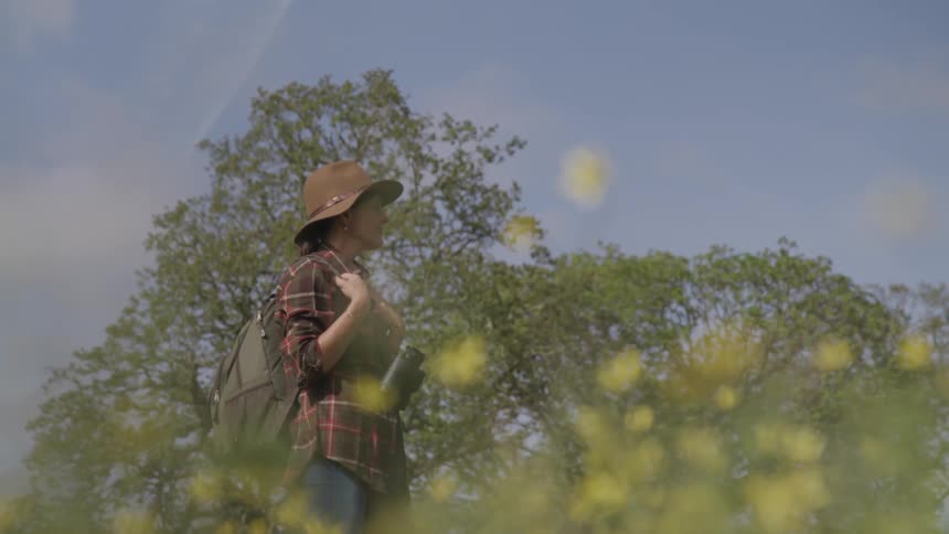 Woman standing in a field wearing a sun hat