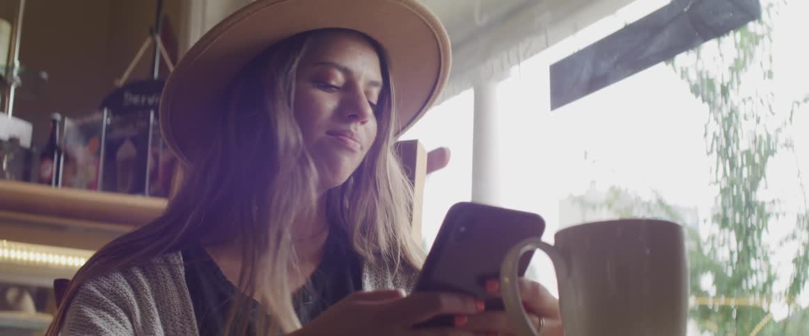 A woman sits at a table looking at her cell phone