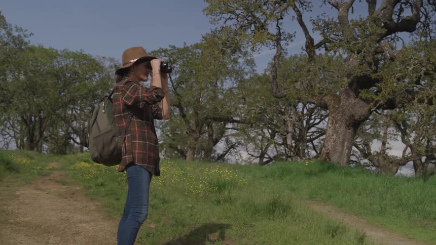 A female hiker looking through binoculars on a sunny day