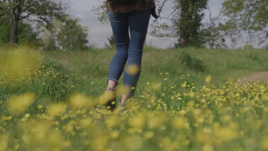 A woman walks through a field of flowers