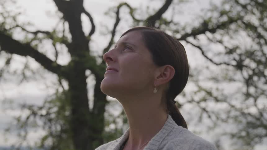 A woman silently looks up into the sky