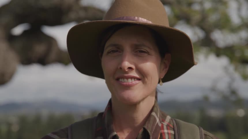 A woman is standing outdoors and smiling