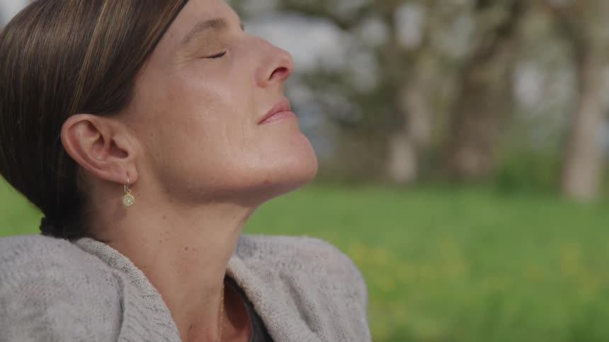 A woman sits in the grass and takes a deep breath