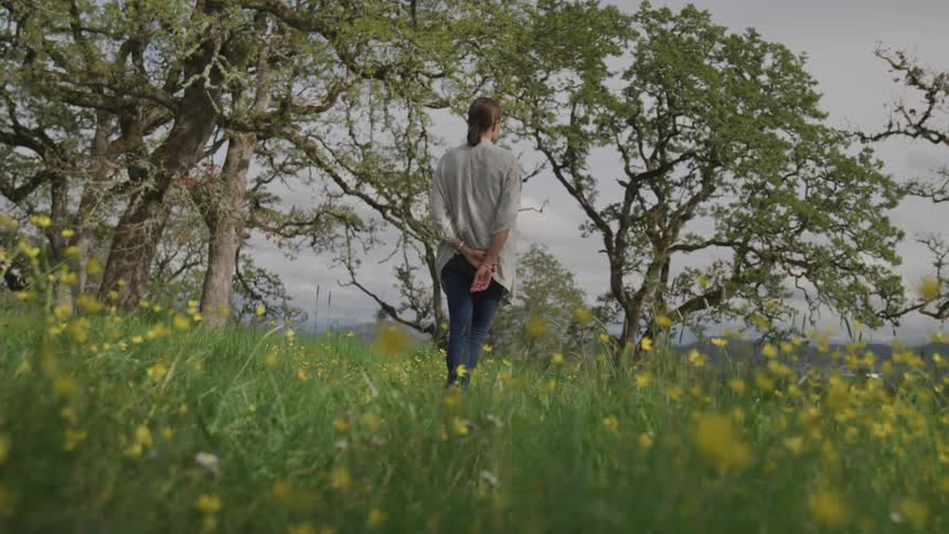 A woman stands in a field of flowers