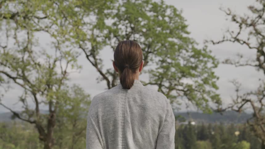 Woman stands and looks around in the forest during daylight