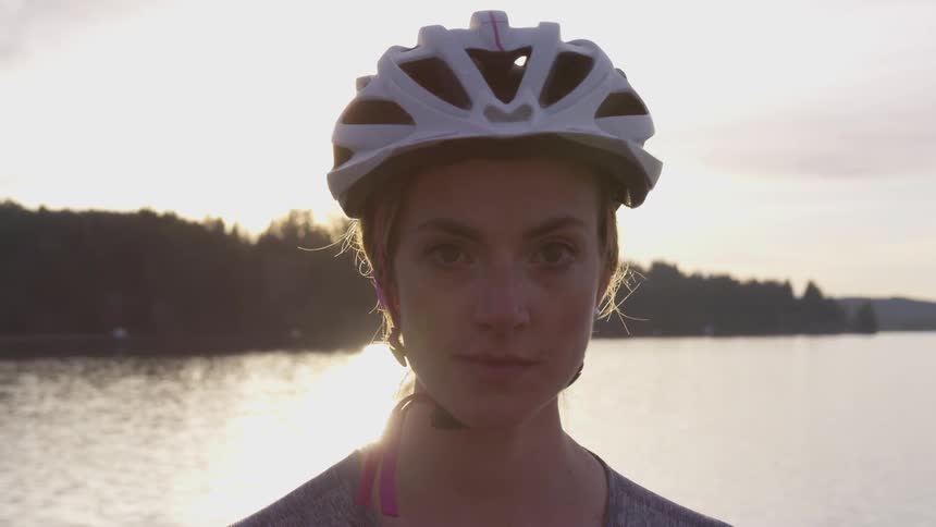 Woman in a cycling helmet stands on a river bank