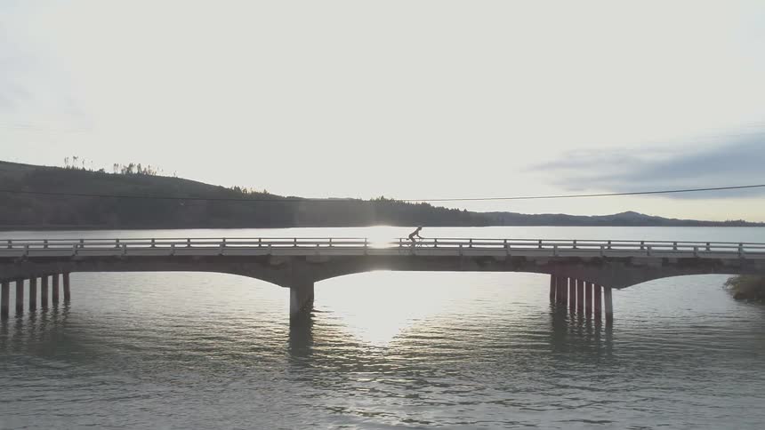 A person rides their bike across a bridge