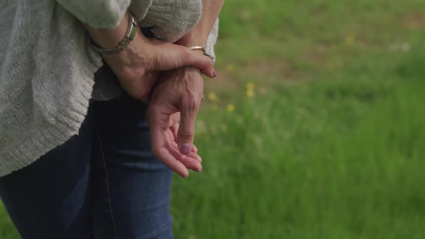 Woman stands hands behind on the grass during daylight