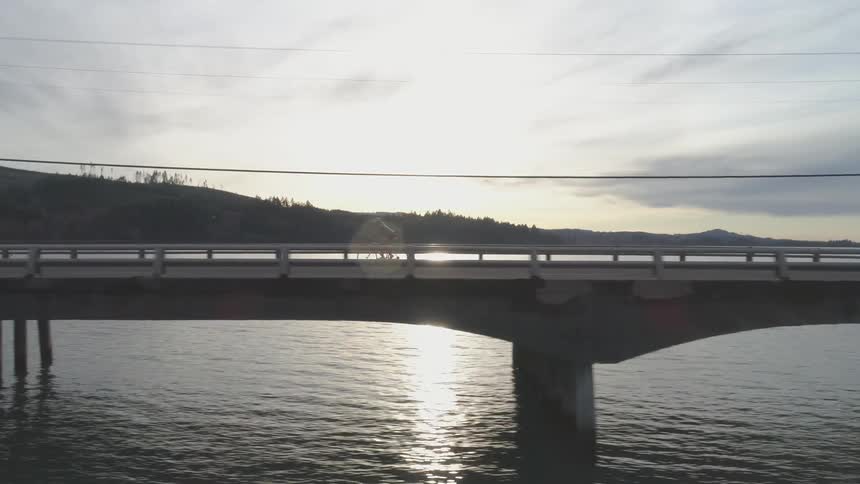 A person bikes across a bridge over water