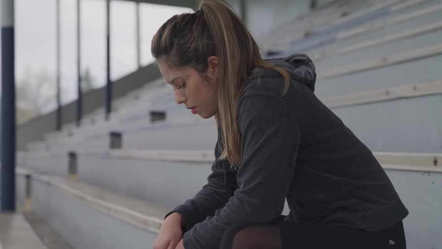 A woman sitting on outdoor bleachers during the day