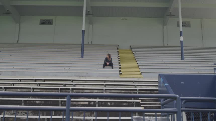 Sad blonde female sitting on bleachers