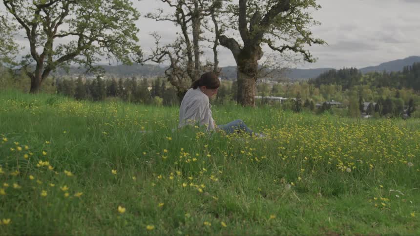 A young woman sits in field of flowers