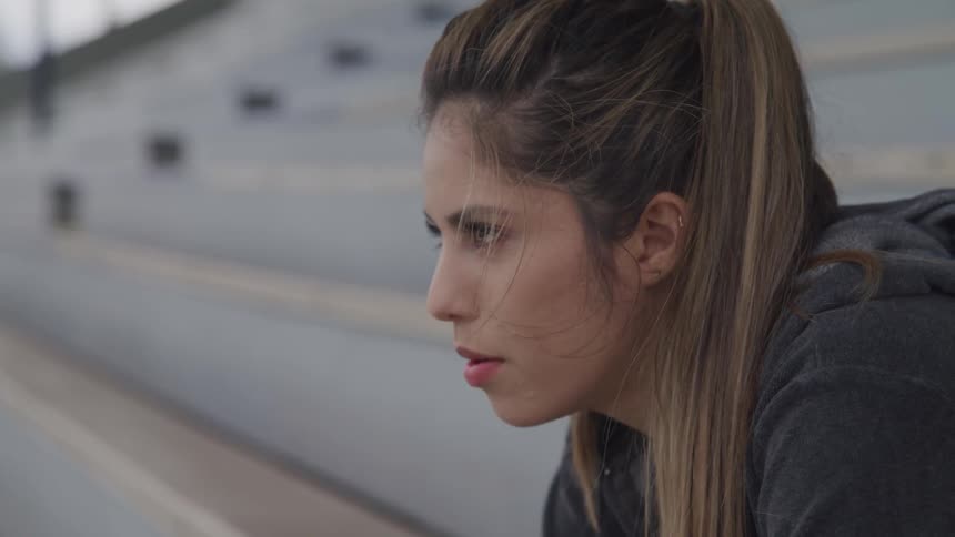 A woman sitting on the bleachers staring off into the distance