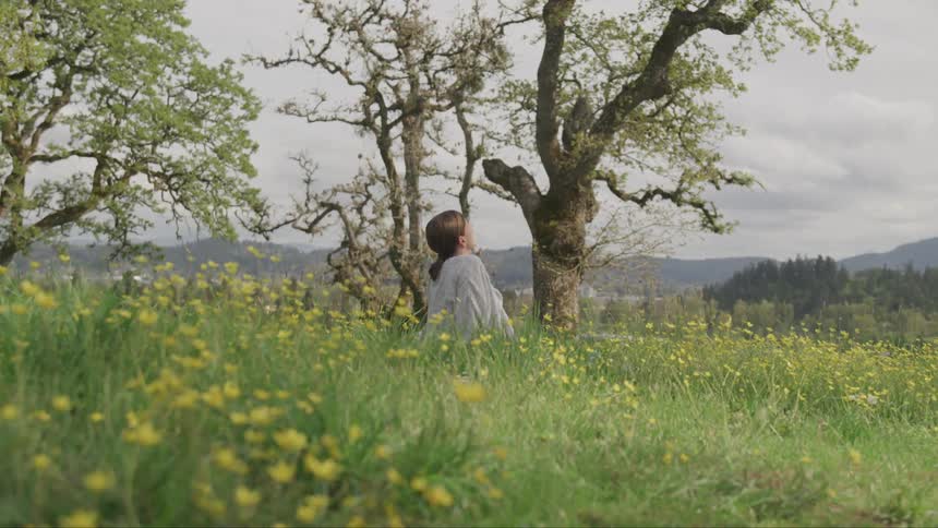 A young woman sits in a field of flowers