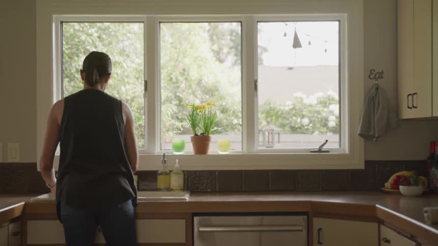 A woman does dishes at the kitchen sink