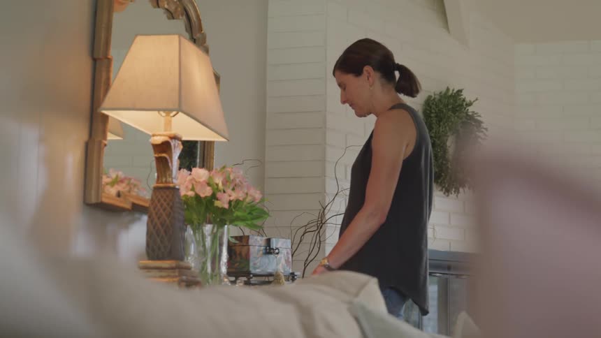 A woman is looking at a mirror in her room
