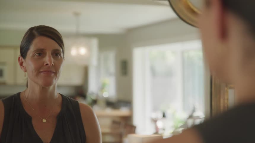 Woman looks in the mirror and smiles at home during daylight