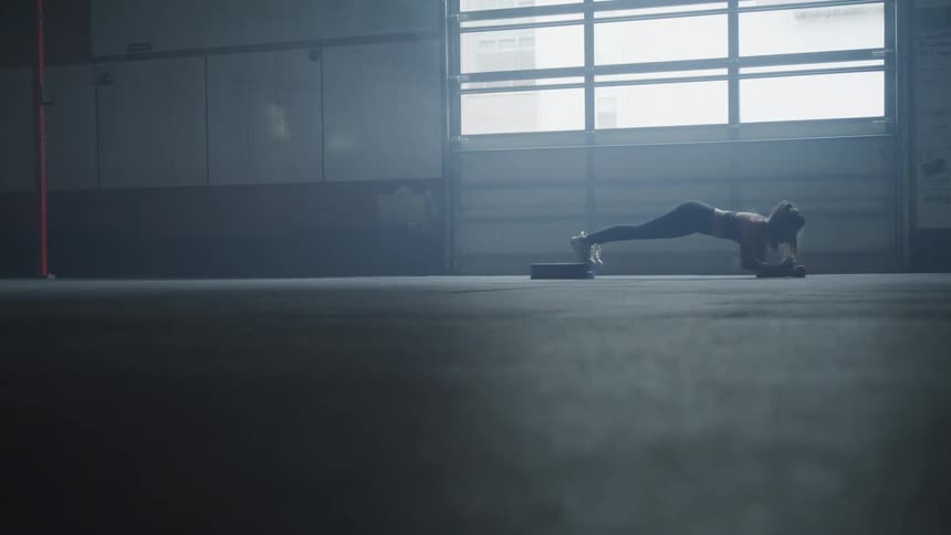 A woman performs press ups in a gym