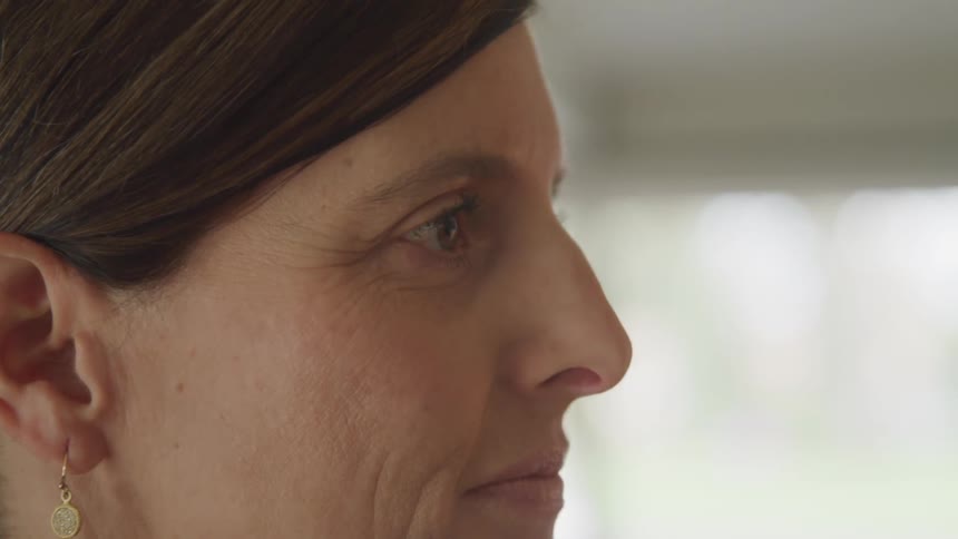 A woman with brown hair is wearing earrings