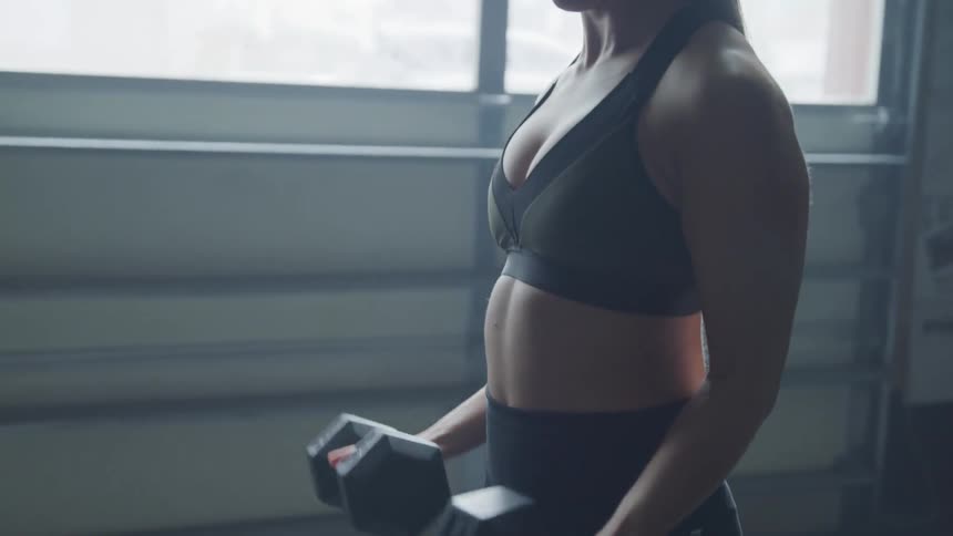 Woman lifts dumbbells indoors during daylight
