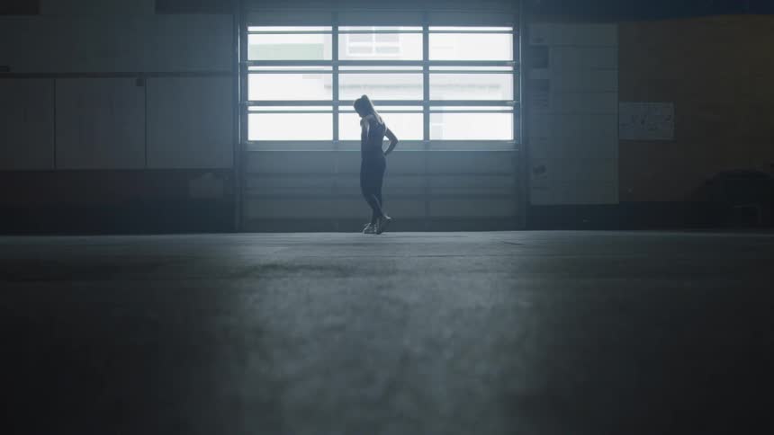 Woman stands and walks around in front of the window in a big room during daylight