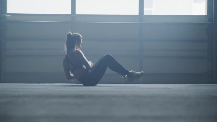 A woman works out and twists with a weighed ball