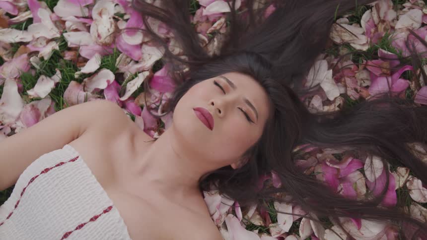 A woman sleeping in a bunch of pink flowers peacefully