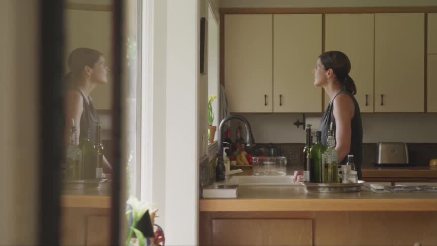 A woman standing in a kitchen staring out the window