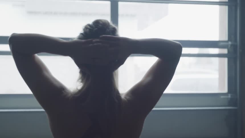 A woman in fitness clothes stands behind the large window