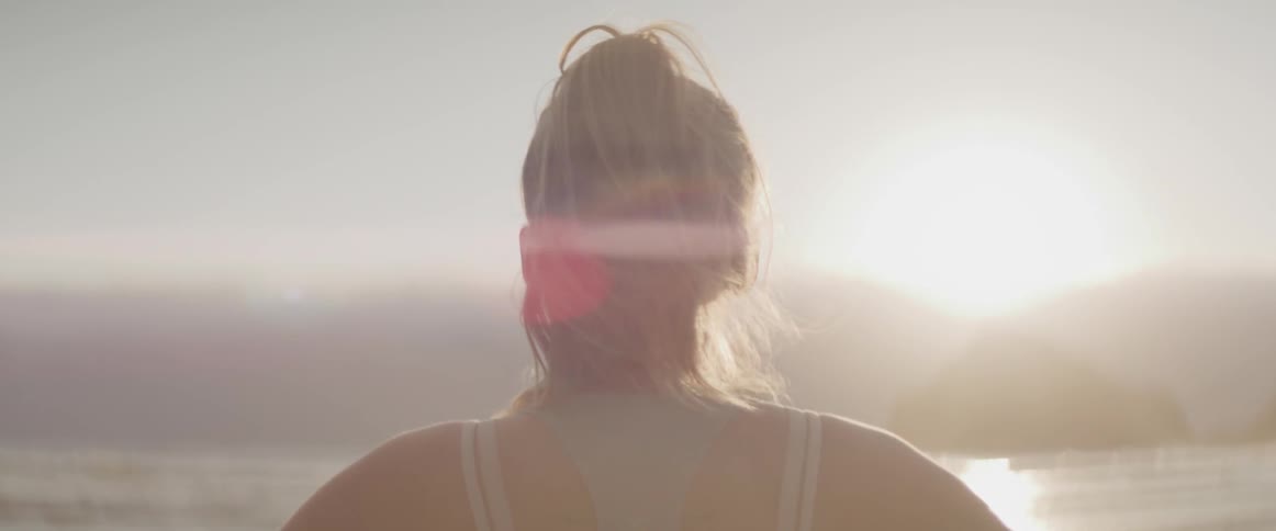 Woman stands on beach at sunset