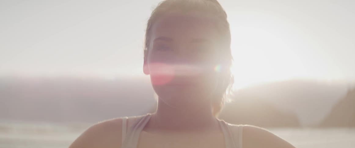 A young white woman in a tank top looks into the camera