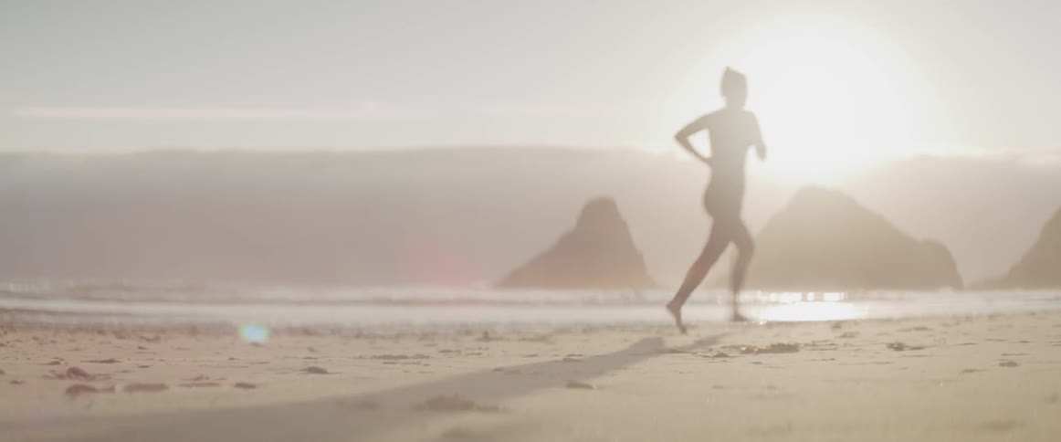 A woman is jogging along the coastline