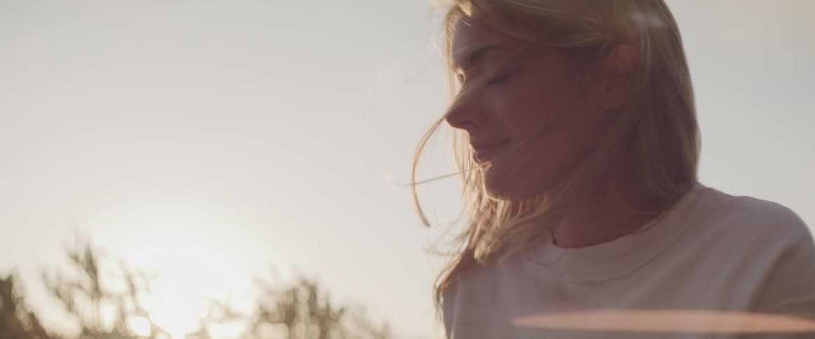 Blonde woman stare into the sky and brush her hair with her hands