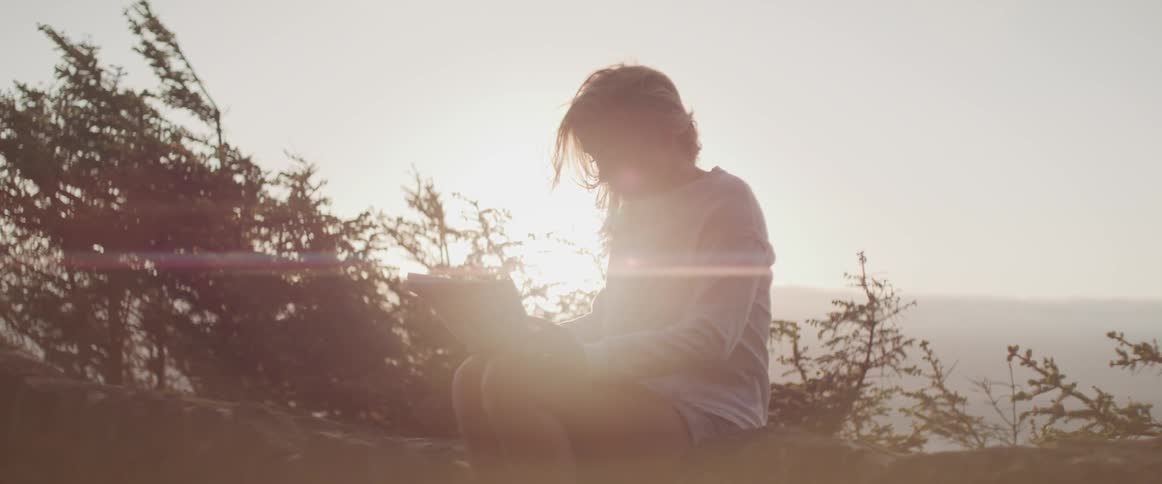 Girl reading a paper by water