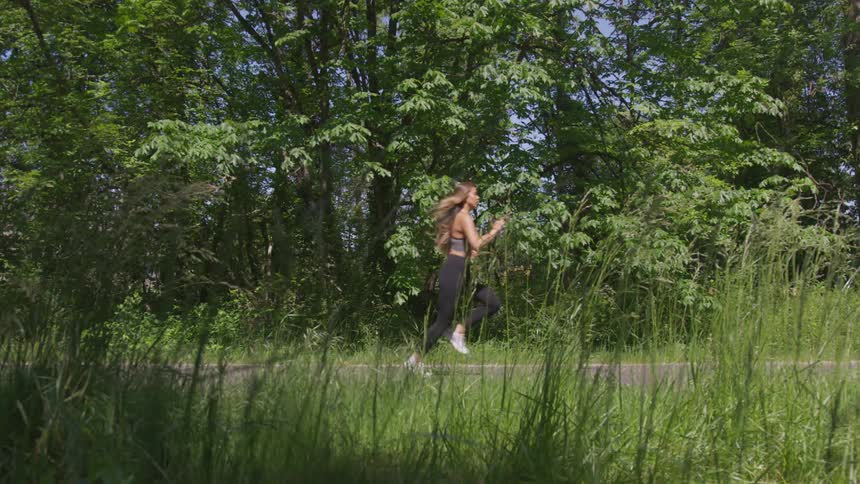 A woman is jogging outdoors in a wooded area