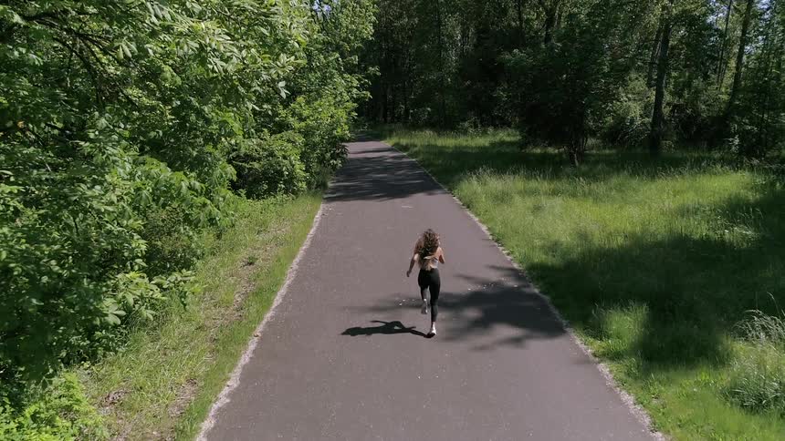 A woman is jogging outdoors on a path