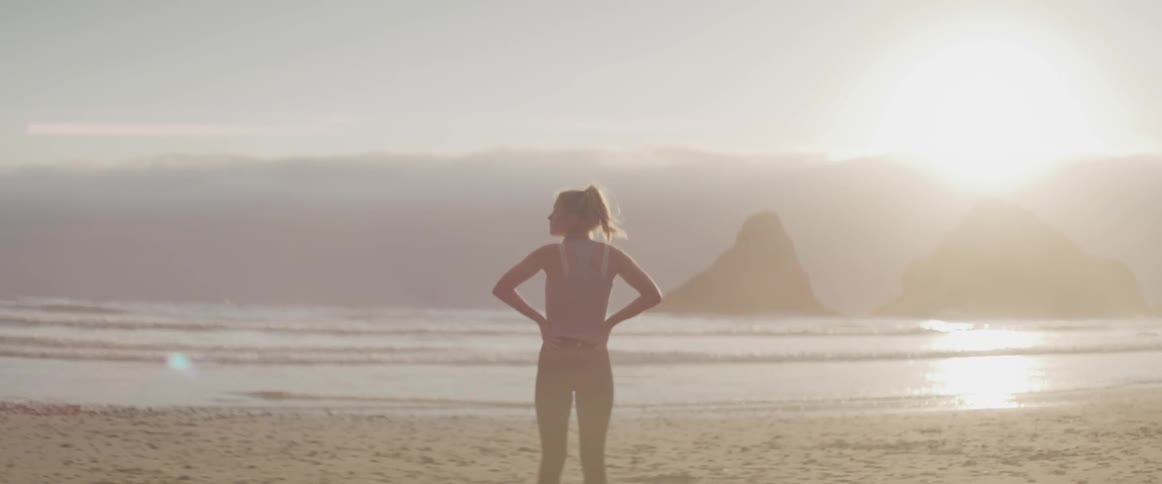 Woman stands on the beach in the sun
