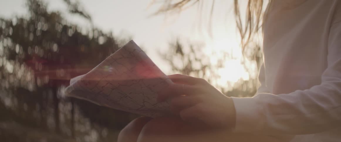 A girl sitting outdoors reading a map
