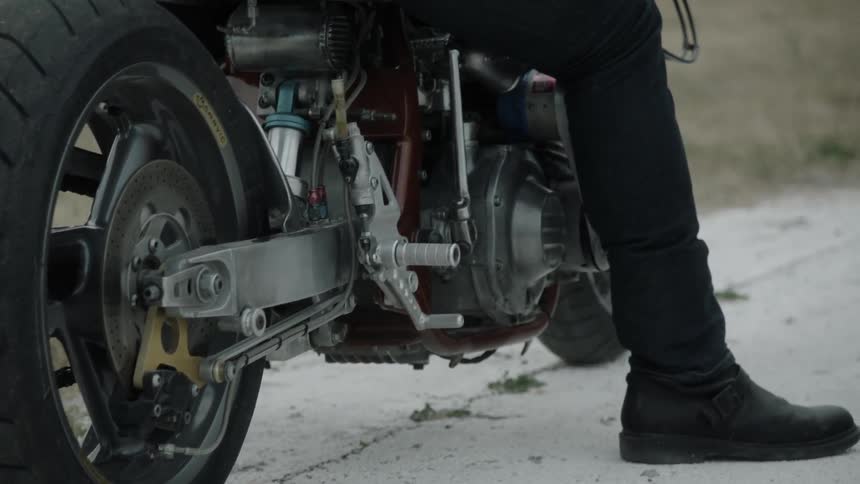 A person sits on a stationary motorcycle