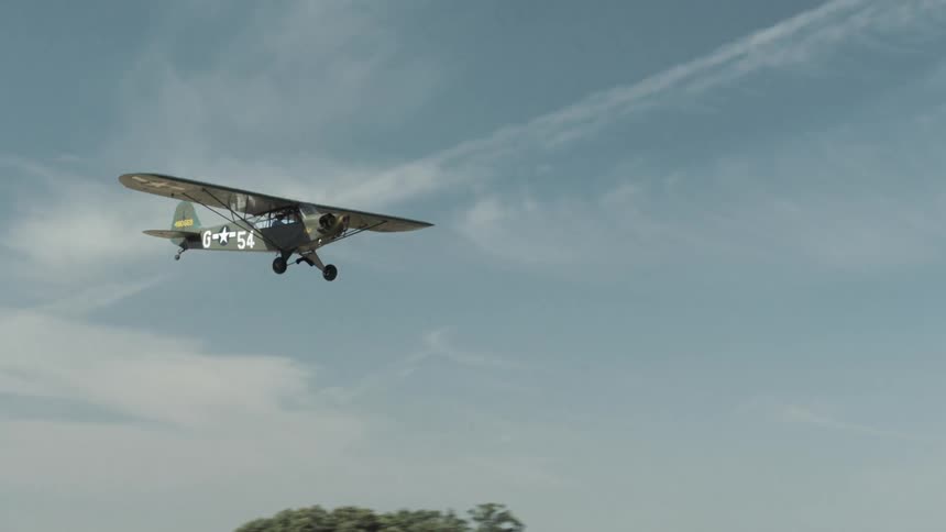 A military plane with a propeller and single wing flies through the sky