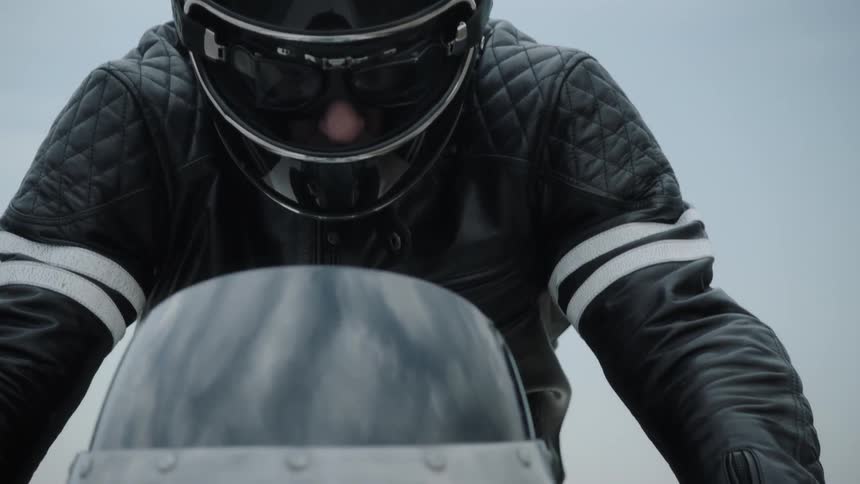 A man wearing a helmet and black jacket rides a motorcycle