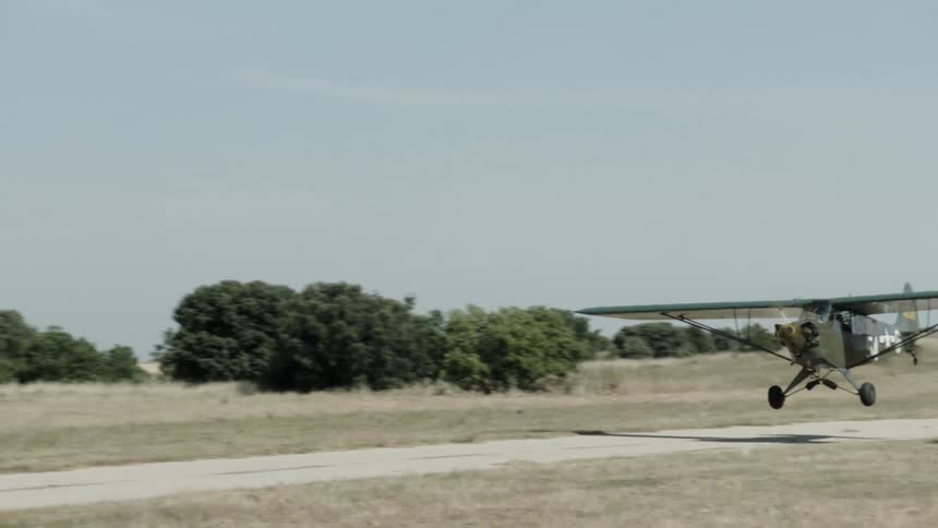 Vintage small plane taking off from a dirt runway in a rural area