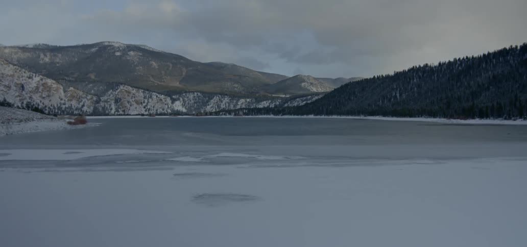 A scenery of a lake and mountain on a cloudy winter
