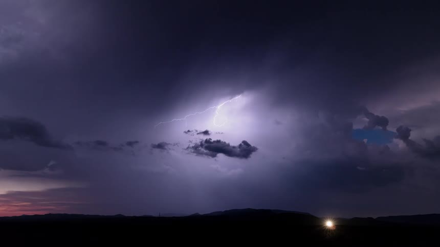 Lightning flashes in the sky during a storm over a rural road