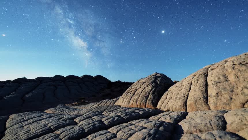 A rocky cliff with the sky and stars in the background
