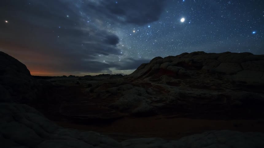 A rocky canyon with the sky and the stars in the background