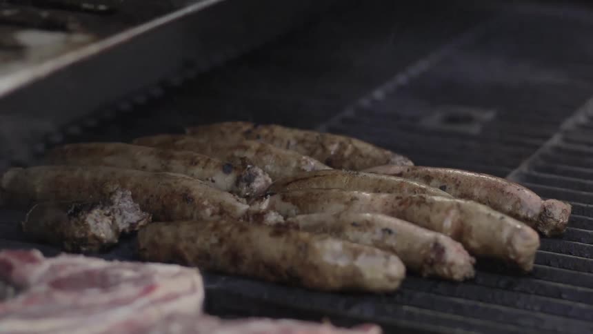 Meat Cooking on Grill Outdoors Over Open Flame in Casual Barbecue Setting.