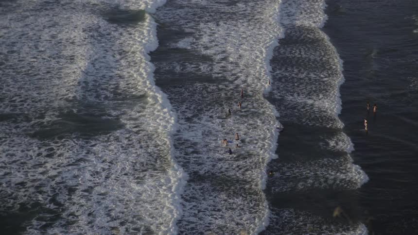 People are in the water as waves pass by them