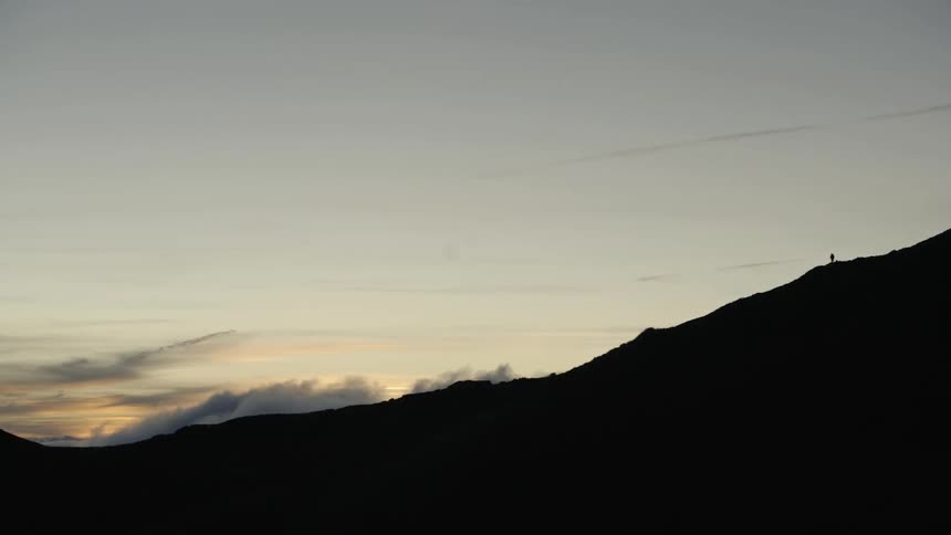 A hill at dusk with the sky and clouds in the background